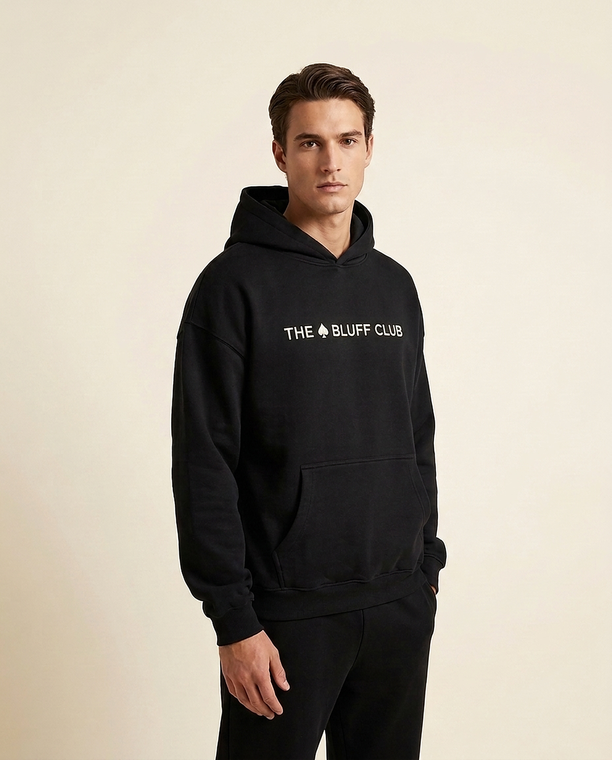 Joueur en hoodie noir The Bluff Club, capuche relevee, style poker premium